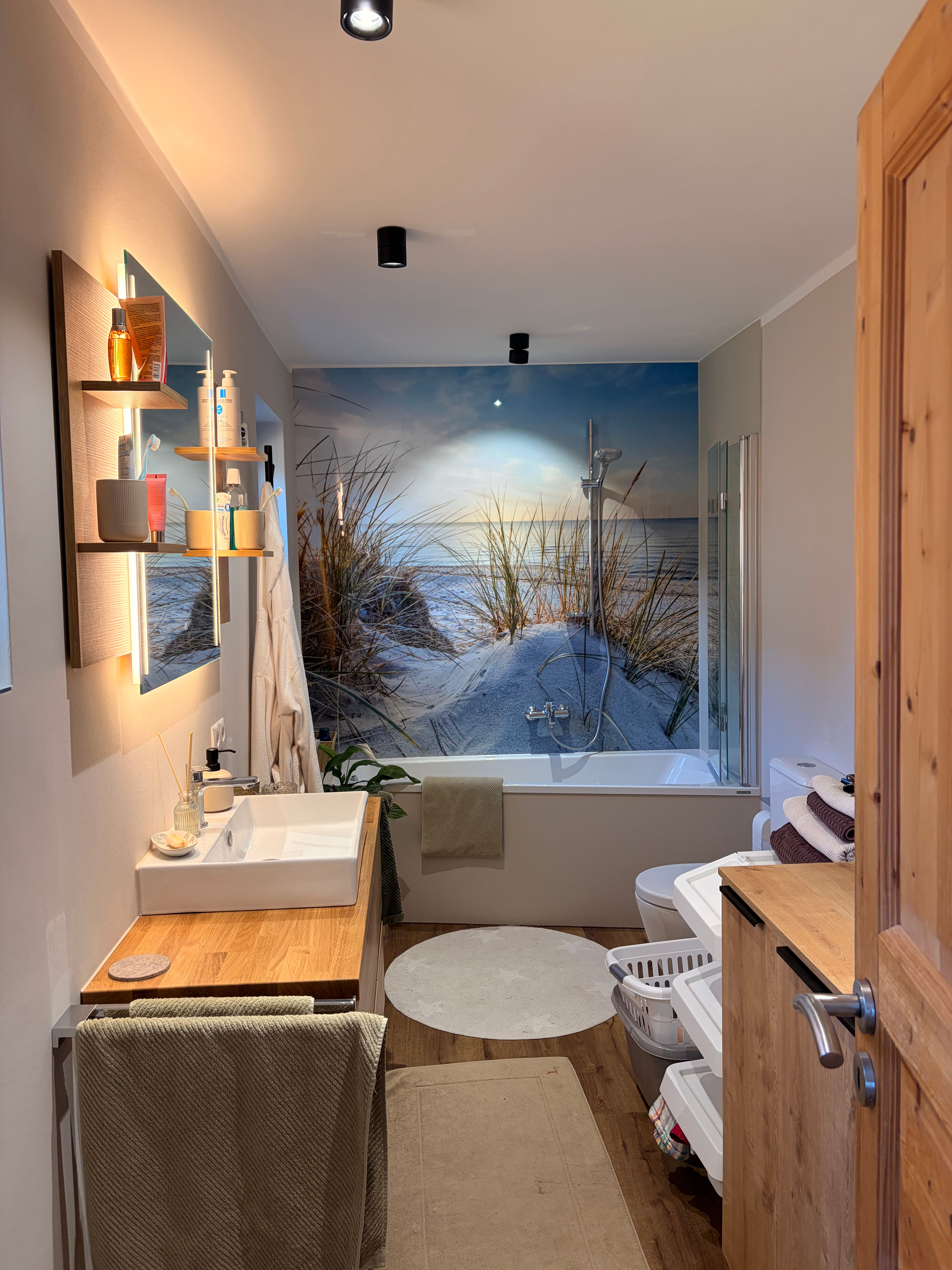 Barrierefreie Dusche mit bodengleichem Ablauf, schwarzer Regendusche, Handbrause und eingebautem Wandfach mit Beleuchtung.