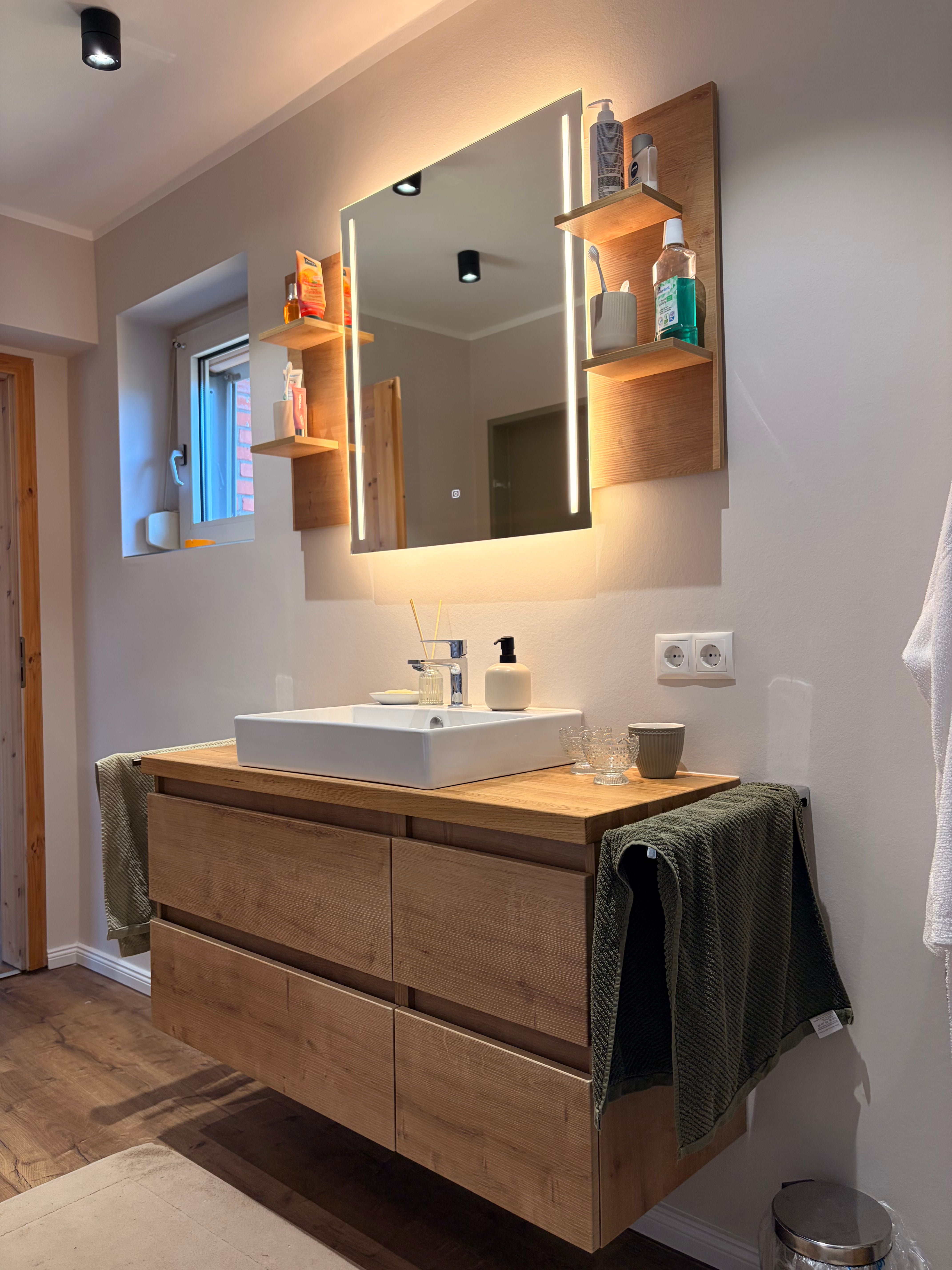Modern barrierefreie Dusche mit transparenten Glaswänden, integriertem Sitz und Holzboden im Badezimmer.