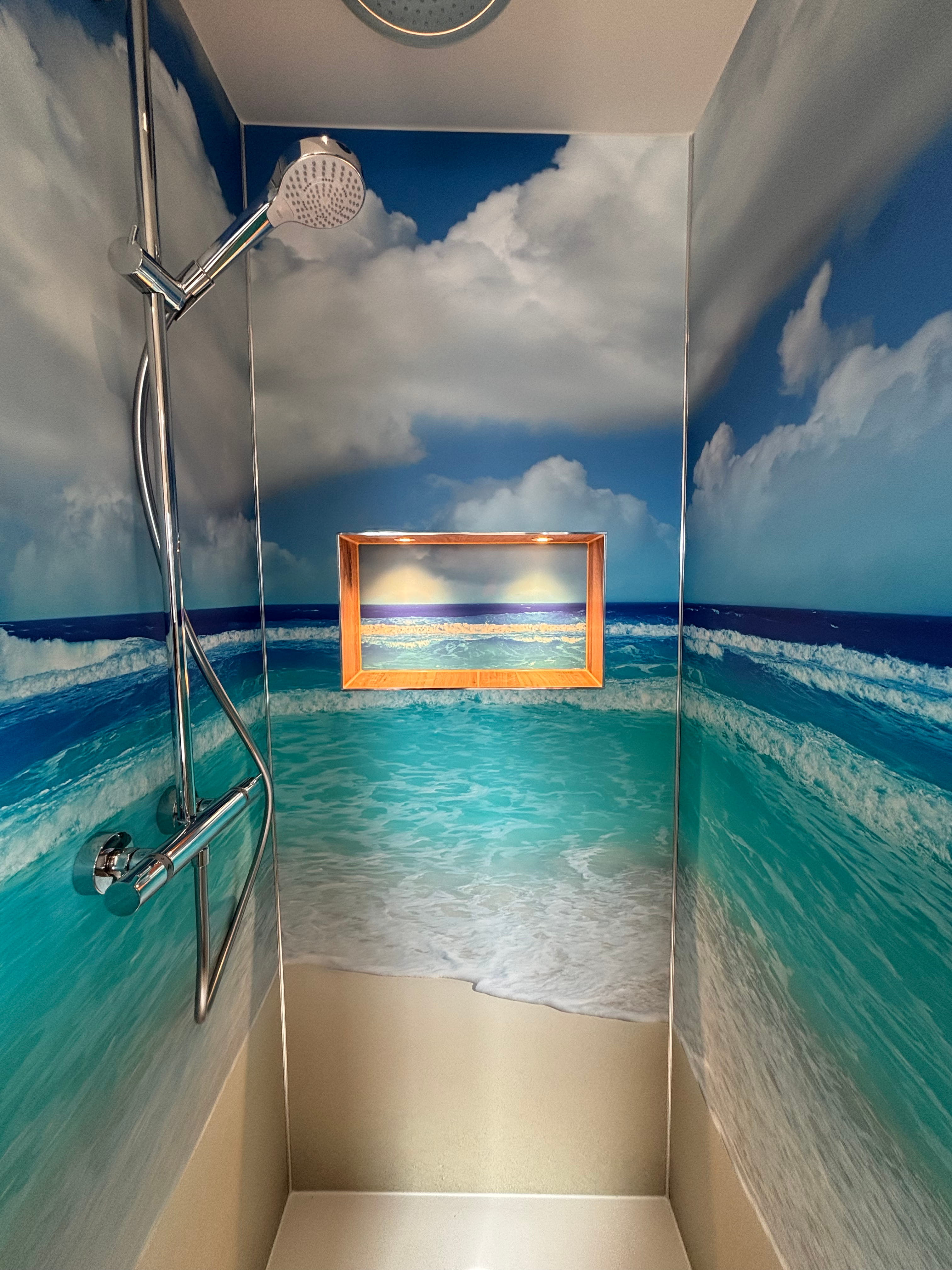 Barrierefreie, moderne Dusche mit Glaswand, schwarzer Duscharmatur und grauen Fliesen.