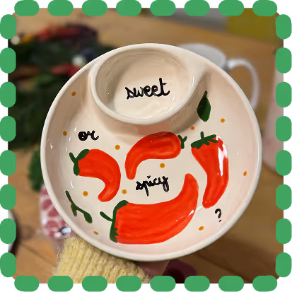 A colorful collection of ceramic dishes, bowls, plates, and pitchers arranged closely together on a table.