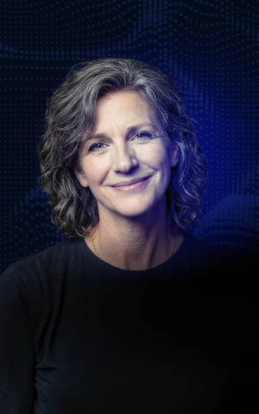 Smiling middle-aged woman with curly gray hair against a blue dotted background.