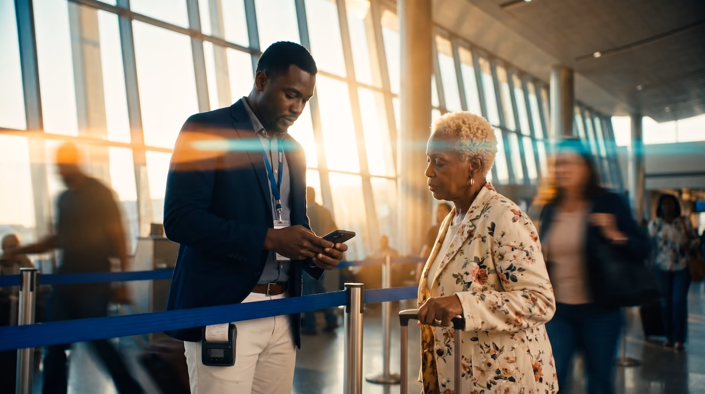 Airport staff checking an elderly passenger’s phone at a screening queue inside a terminal. Using Ink Innovation's mobile technology.