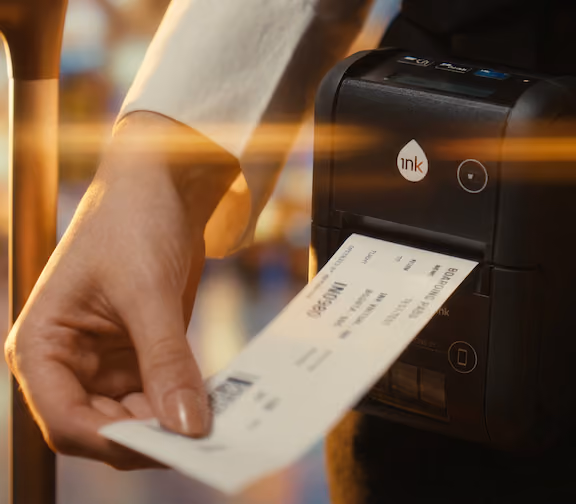 Hand pulling a printed boarding pass from a small portable printer by Ink.