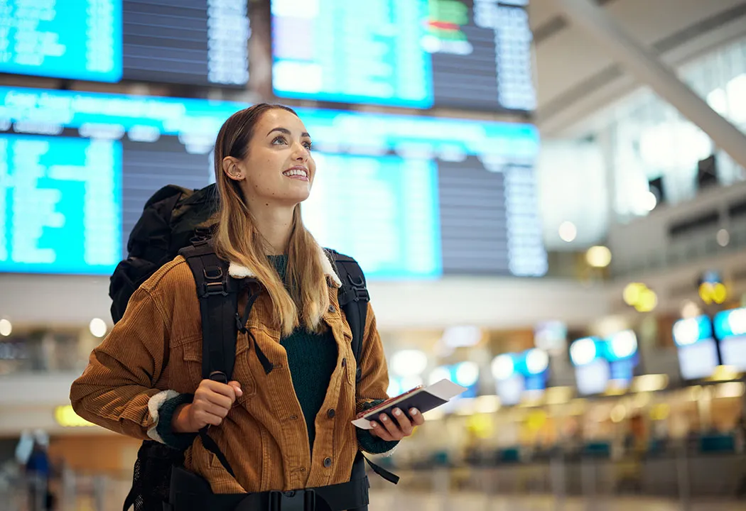 Digital-native traveller at a modern airport using a smartphone, representing the decline of fixed airport hardware