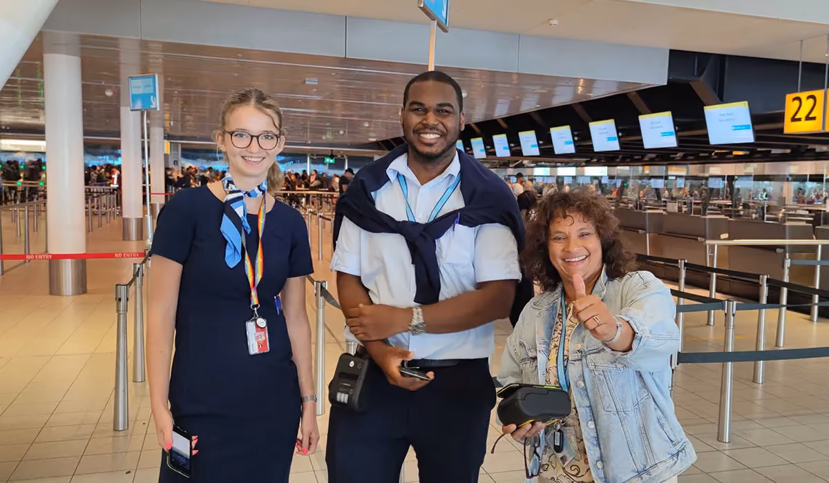 Three airport staff members of TUI posing and giving a thumbs up, wearing portable printers and mobiles - the set of passenger handling solution by Ink Innovation.