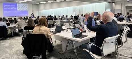 Conference attendees at tables with laptops during a IATA Offers and Orders Forum in Geneva