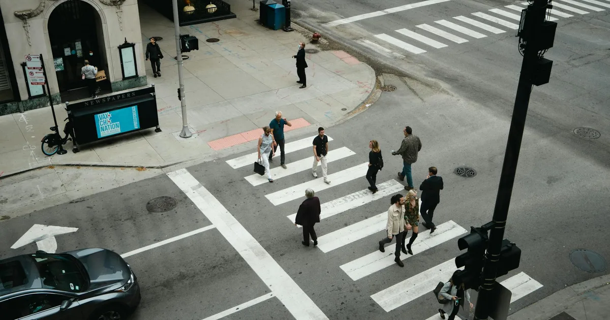 loi badinter piéton — Aerial view of people crossing a city street at a pedestrian crosswalk.