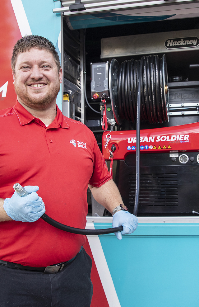 Zoom Drain technician standing beside a truck with hydro jetting equipment.