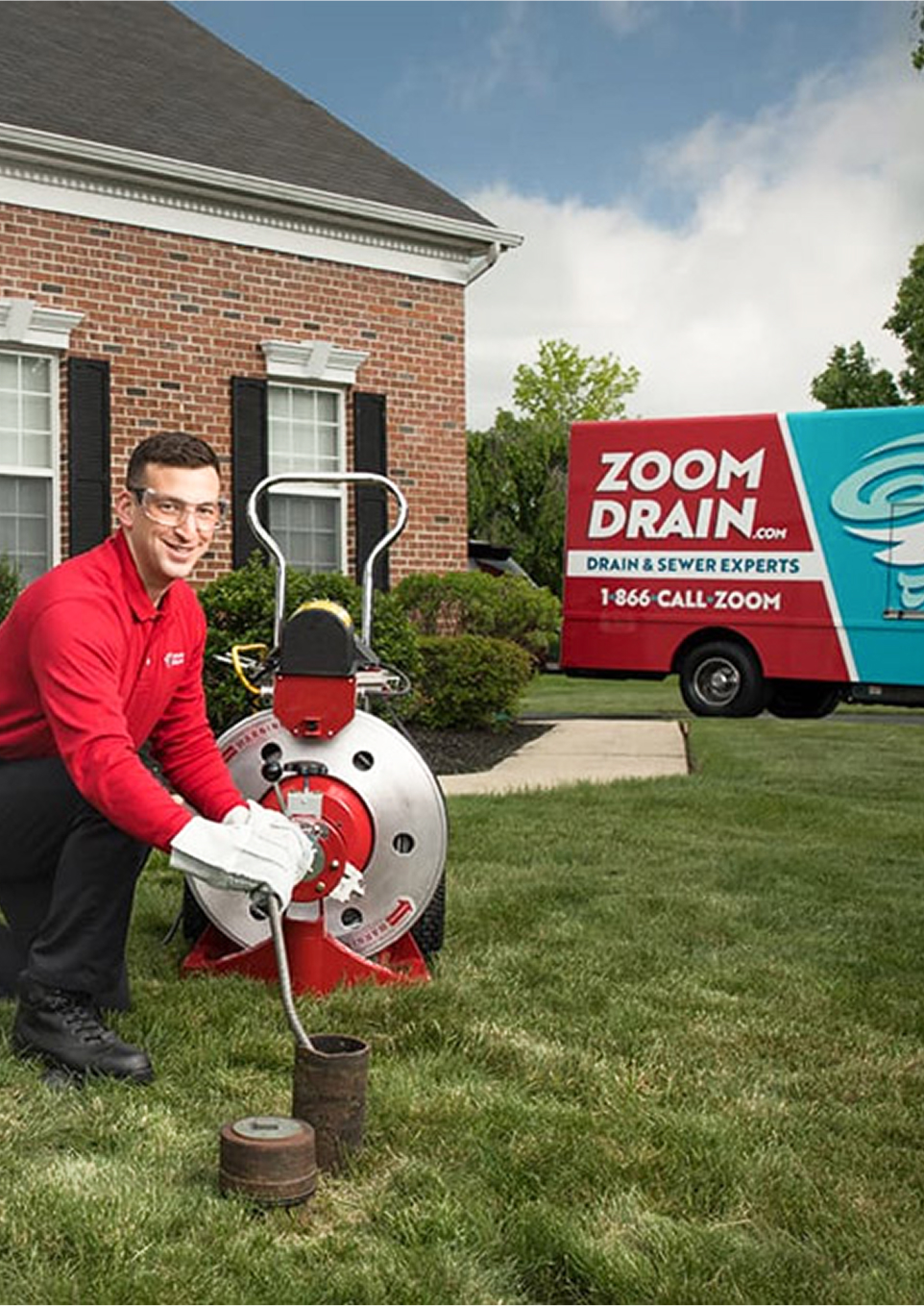 Technician operating drain cleaning equipment on a residential lawn.