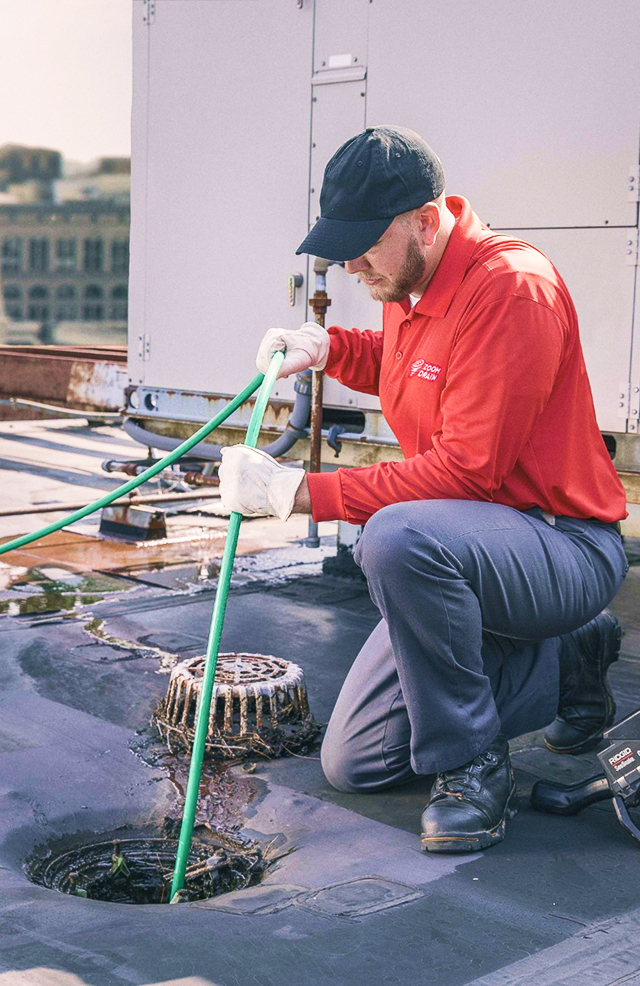 Worker using specialized equipment to inspect underground pipes.