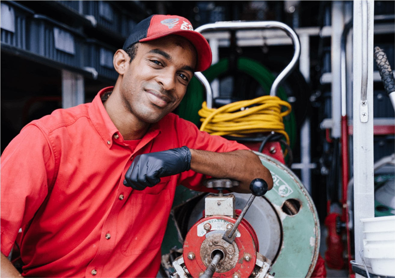 echnician in red shirt working on sewer equipment inside a service truck.