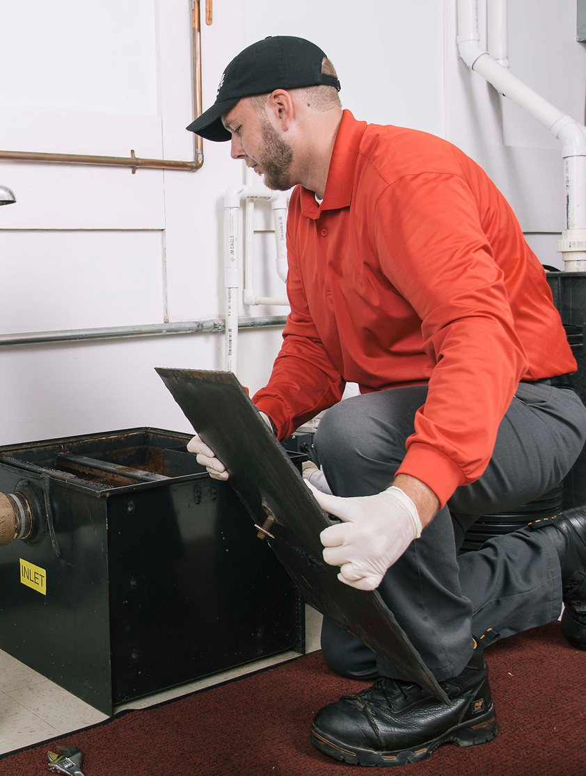 Two workers repairing a residential drain system indoors.