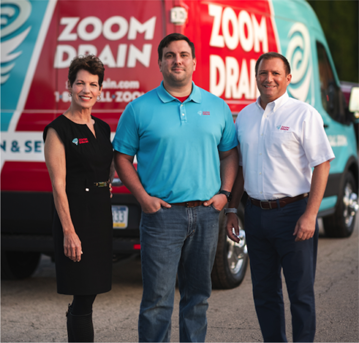 Two men standing in front of a Zoom Drain service truck, smiling at the camera.