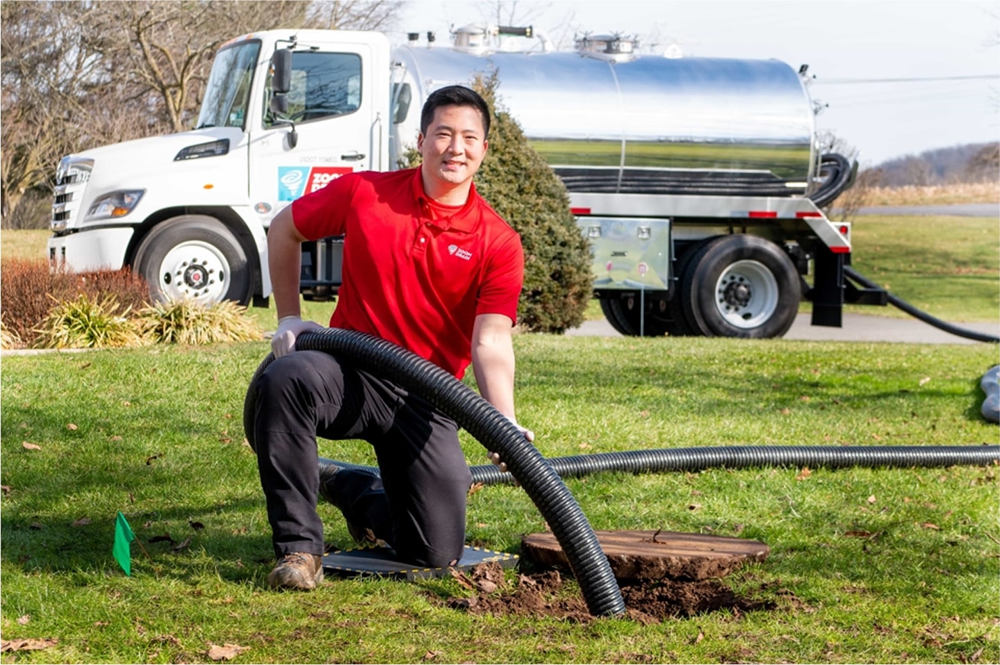 Technician operating drain cleaning equipment in an open grassy area.