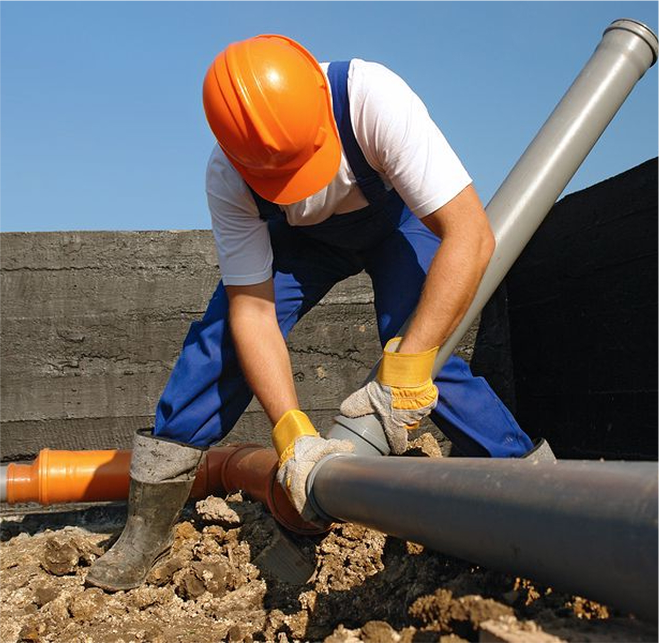 Worker in safety helmet positioning large drainage pipes.