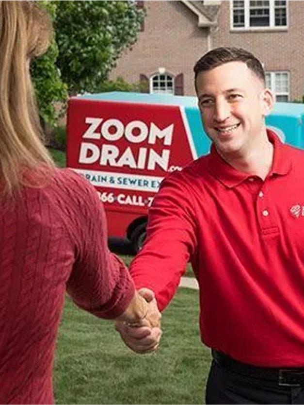 Two Zoom Drain employees shaking hands outside a home.