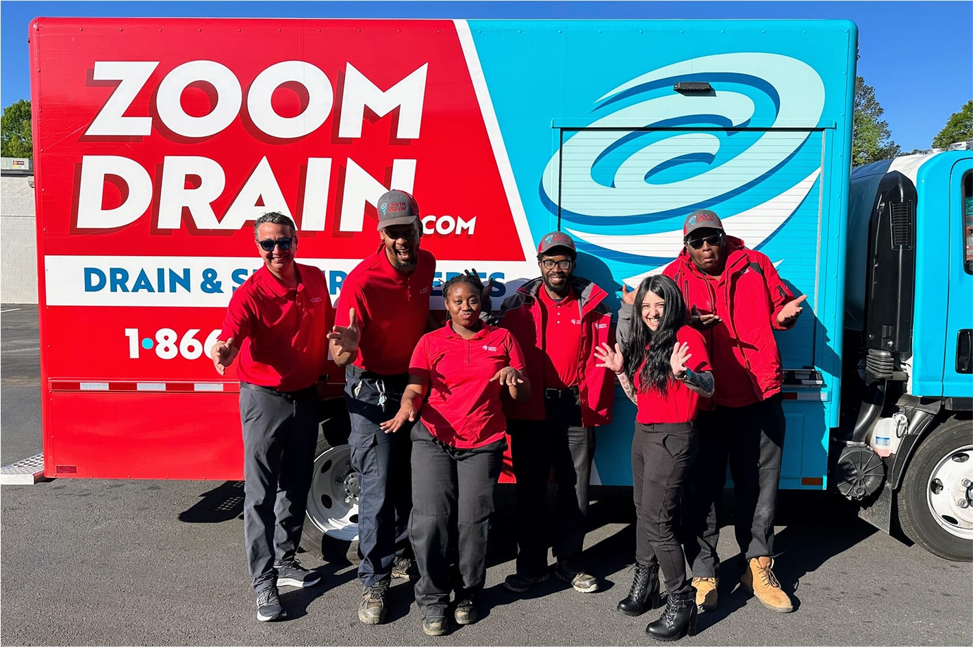 Group of Zoom Drain employees standing together in front of branded vans.