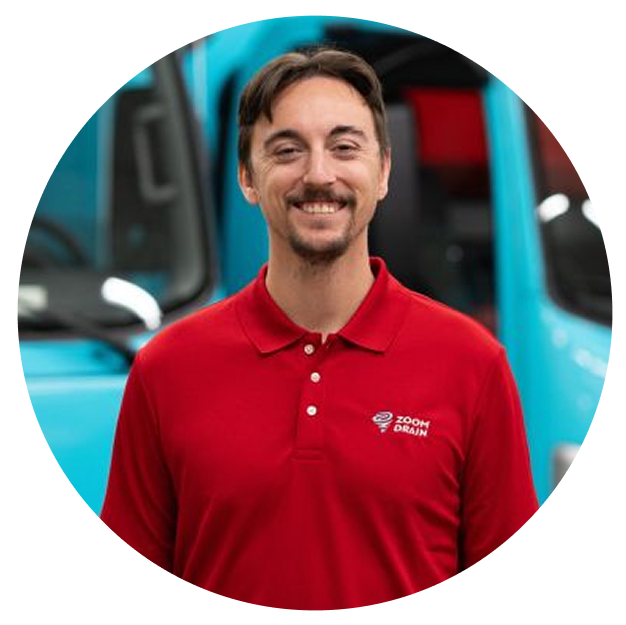 Portrait of a smiling man with short dark hair and mustache in a red Zoom Drain shirt.