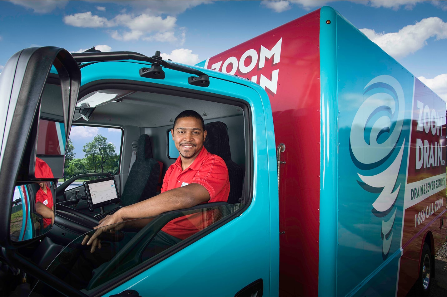 Zoom Drain driver smiling from inside the cab of a company truck.