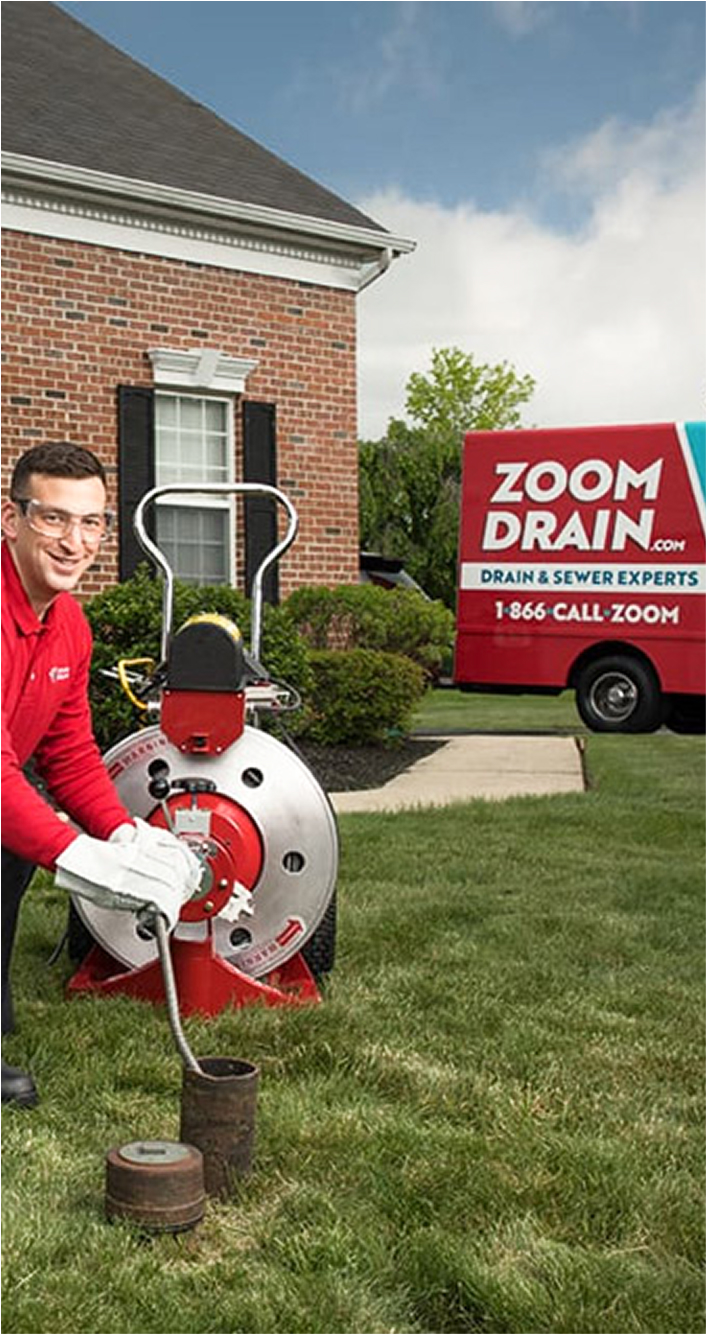 Technician working on an outdoor drain near a residential home.
