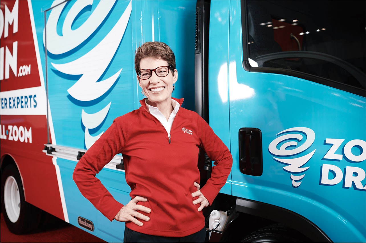 Zoom Drain technician posing in front of a truck holding hydro jetting equipment