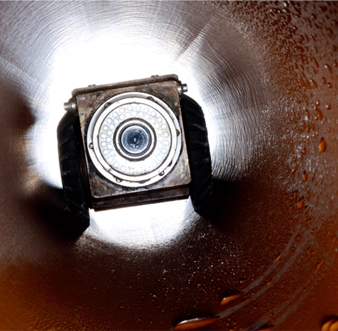 Close-up of a sewer inspection camera head inside a pipe.