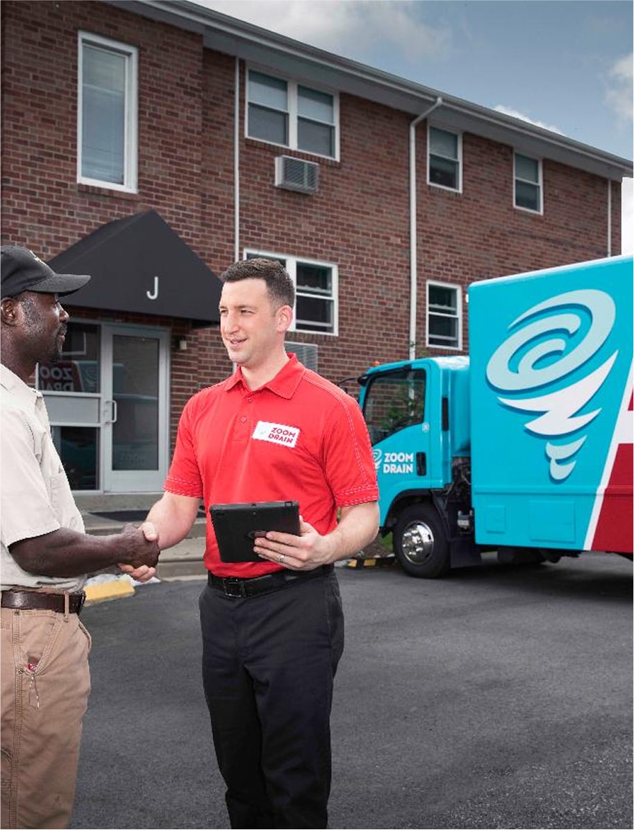 Zoom Drain technician carrying equipment outside a residential property.