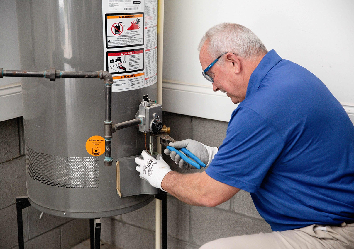 Technician in blue shirt servicing a large commercial water heater.