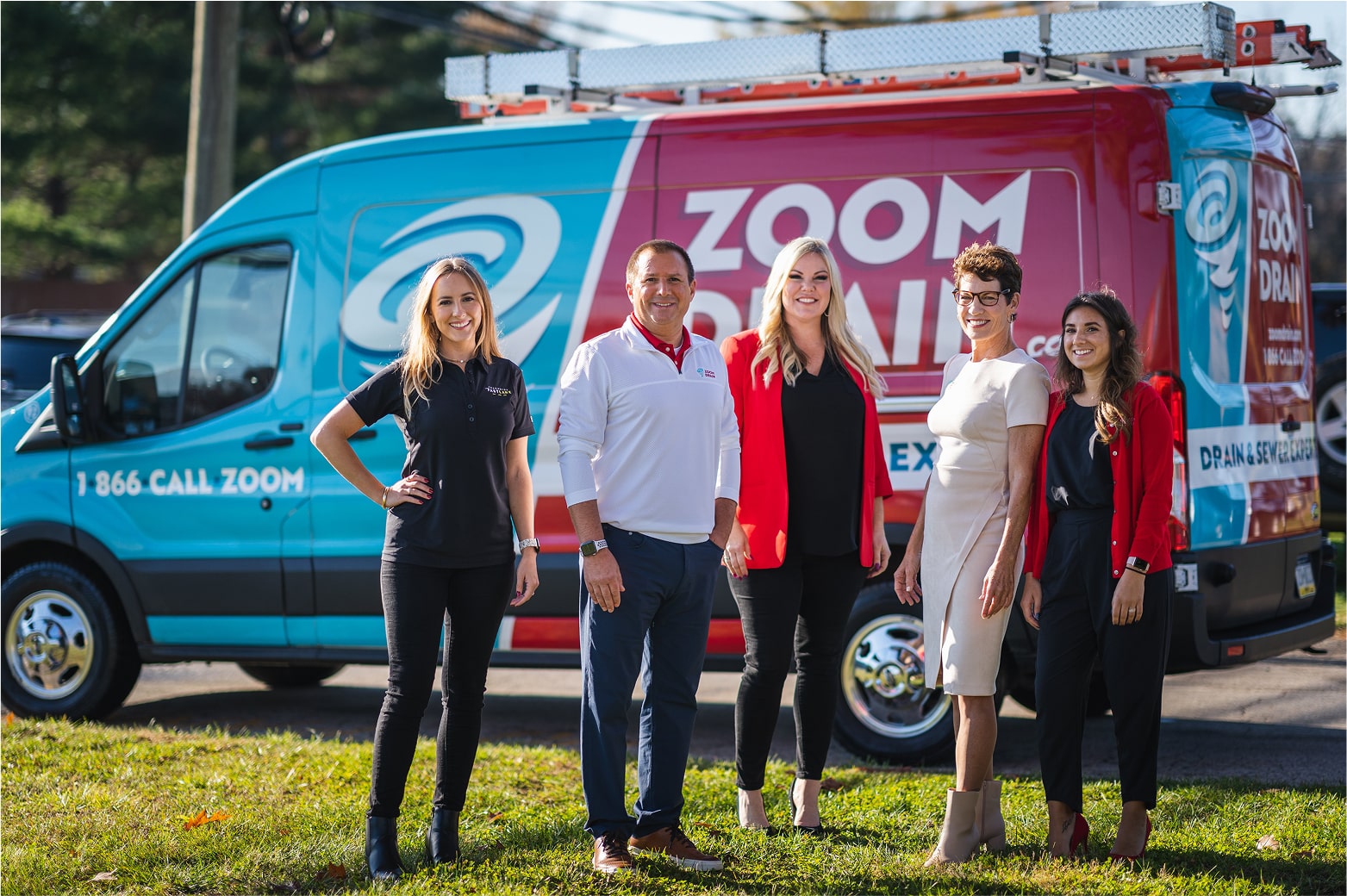 Group of Zoom Drain employees standing in front of company vans.