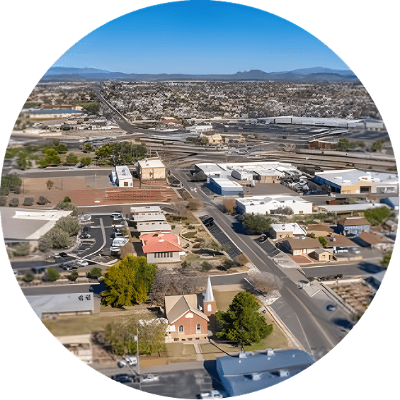 Aerial view of Peoria, Arizona, showing residential neighborhoods, commercial buildings, and tree-lined streets, with distant mountains under a clear blue sky.