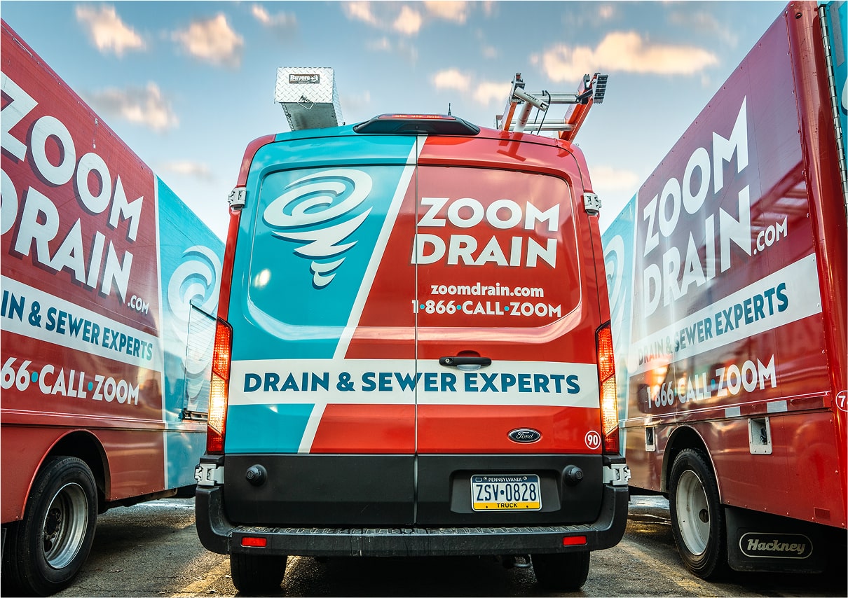 Zoom Drain service trucks parked outside a building.