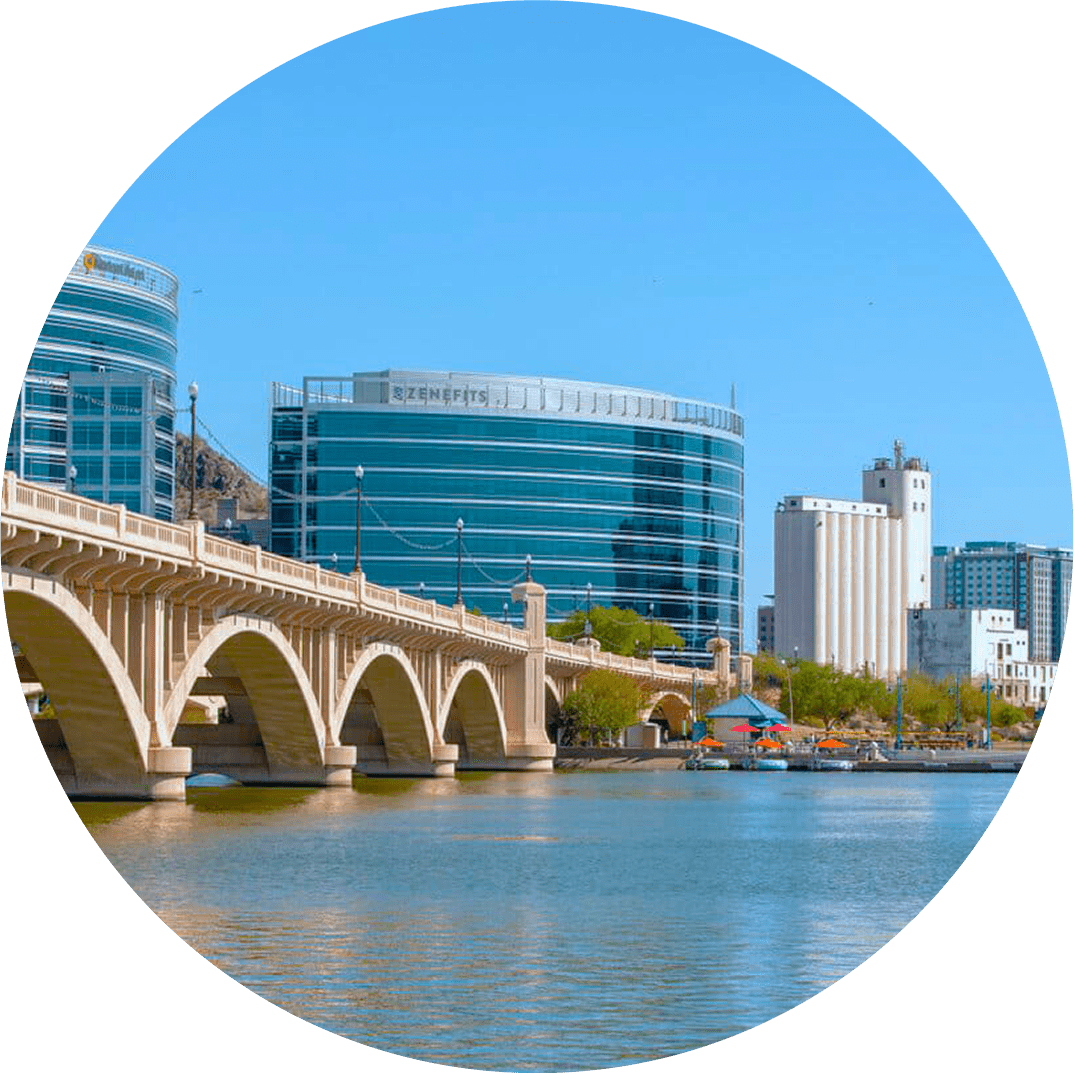 View of Tempe Town Lake with bridge and city buildings in the background.