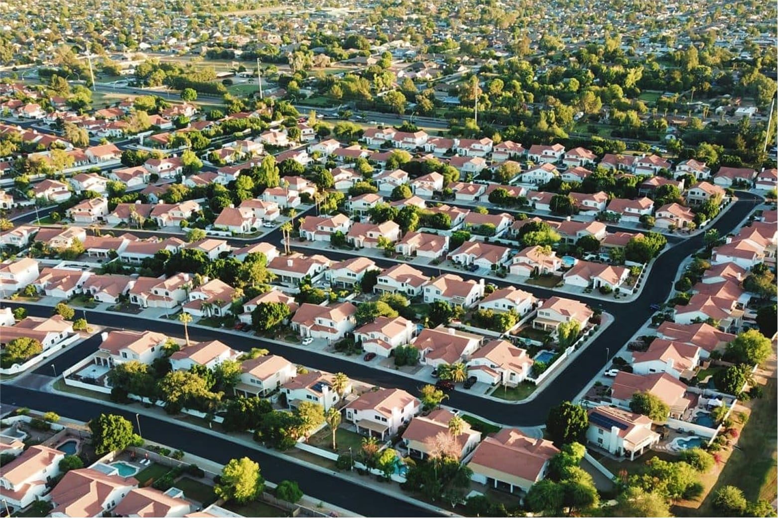 Aerial view of a densely packed suburban area with green lawns and houses.