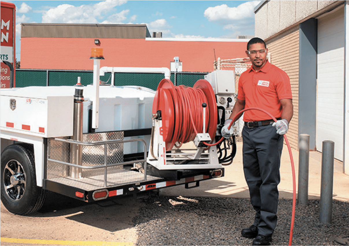 Two uniformed workers standing beside a plumbing service trailer.