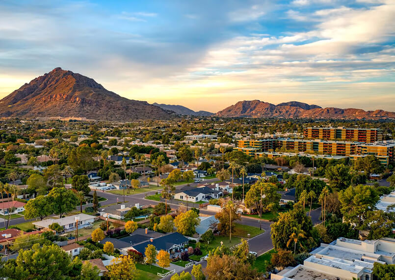 Scenic city view with a large bridge and surrounding mountains under a blue sky.