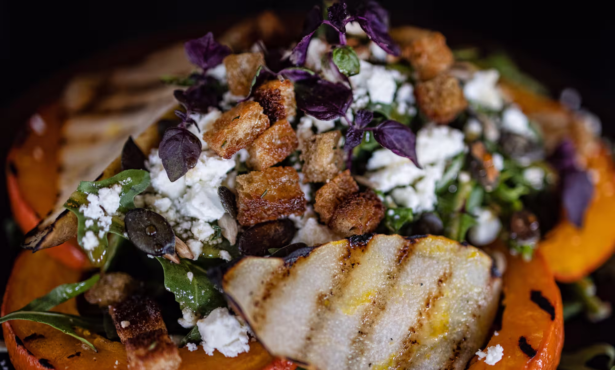 Gegrillter Salat mit geröstetem Kürbis, Croutons, Ziegenkäse und frischen Kräutern.