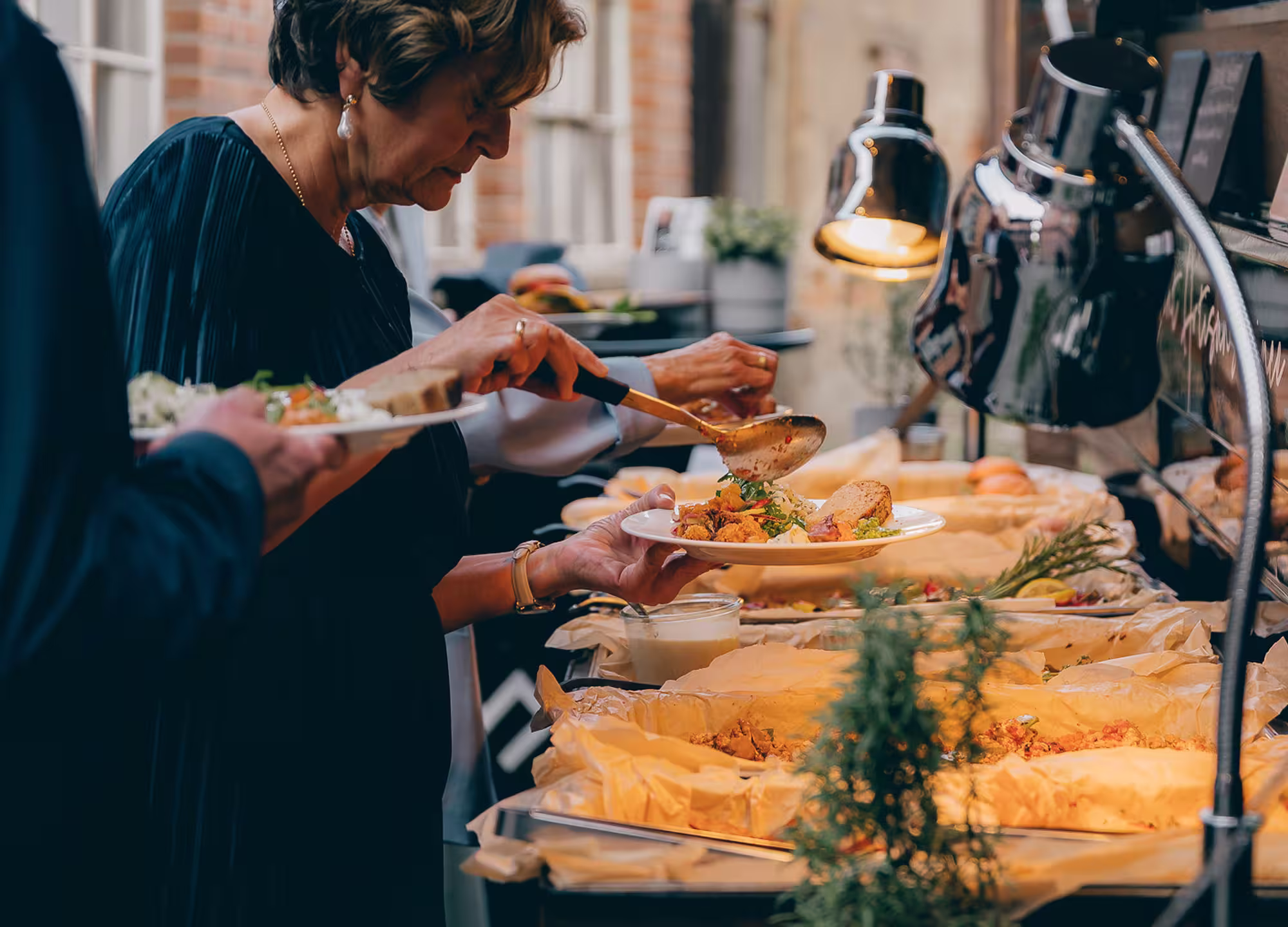 Frau nimmt Essen von einem Buffet bei einer Veranstaltung im Außenbereich.