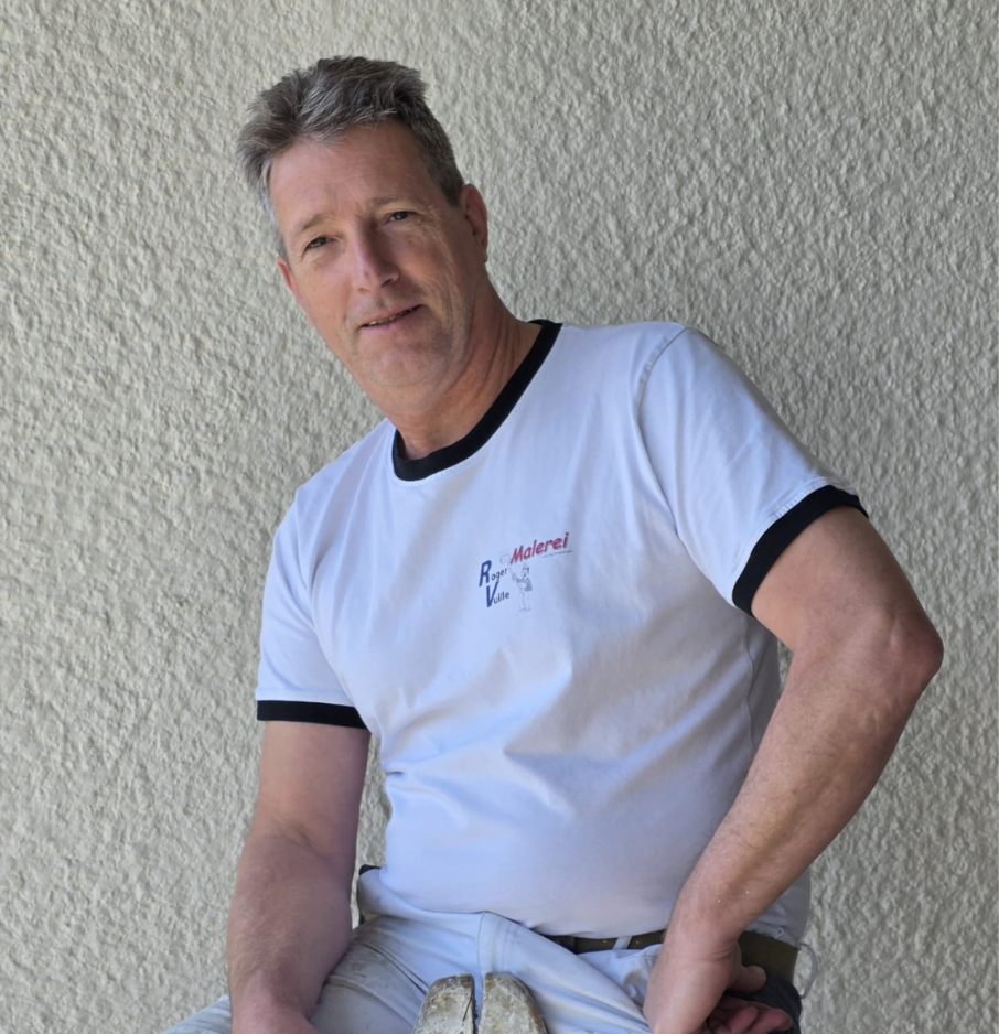 Roger Vuille der auf einer Leiter sitzt und in die Kamera schaut.