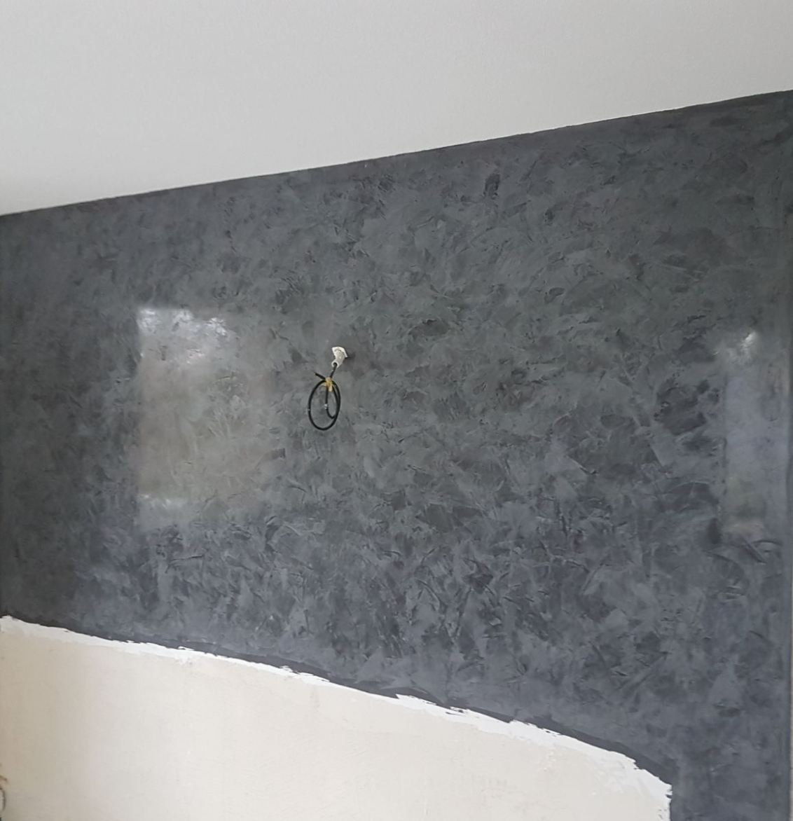 Eine grafische Fototapete mit Pflanzen, Vogel und Blumen. Davor ein grünes Sofa.