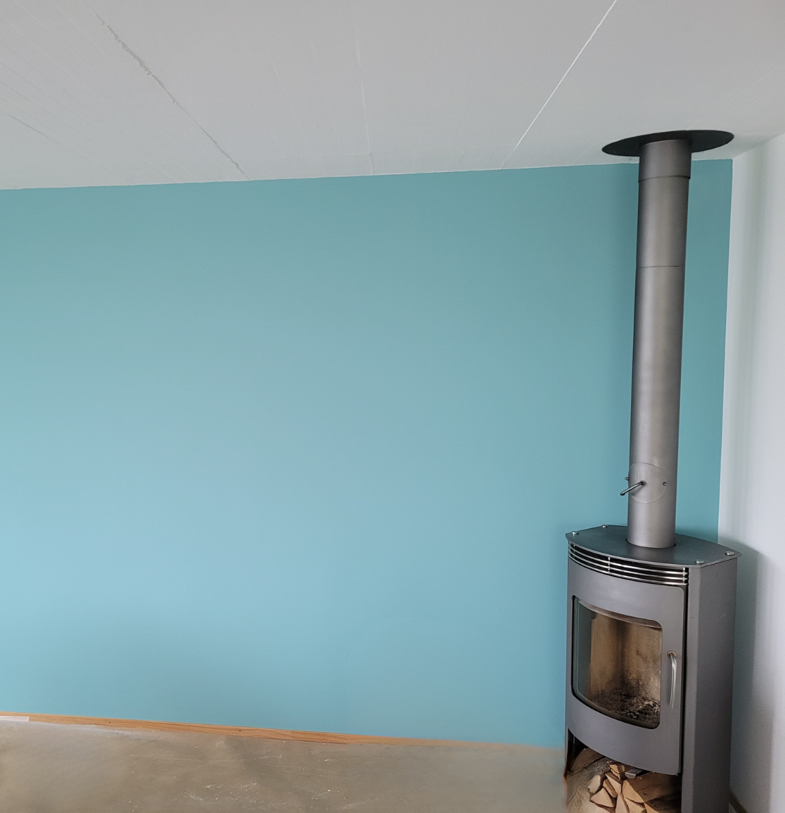 Eine grafische Fototapete mit Pflanzen, Vogel und Blumen. Davor ein grünes Sofa.