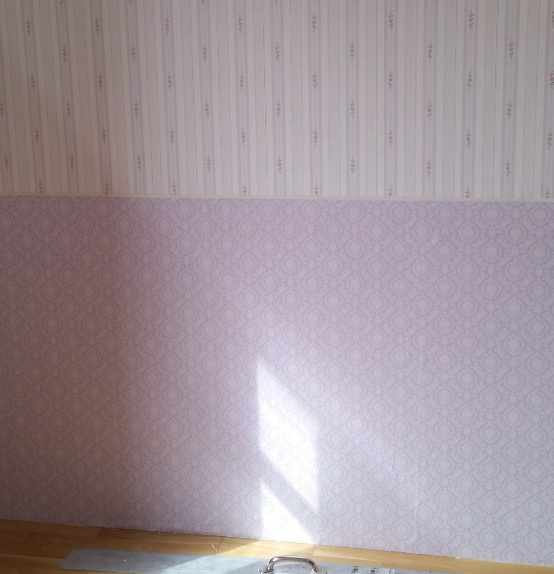 Eine grafische Fototapete mit Pflanzen, Vogel und Blumen. Davor ein grünes Sofa.