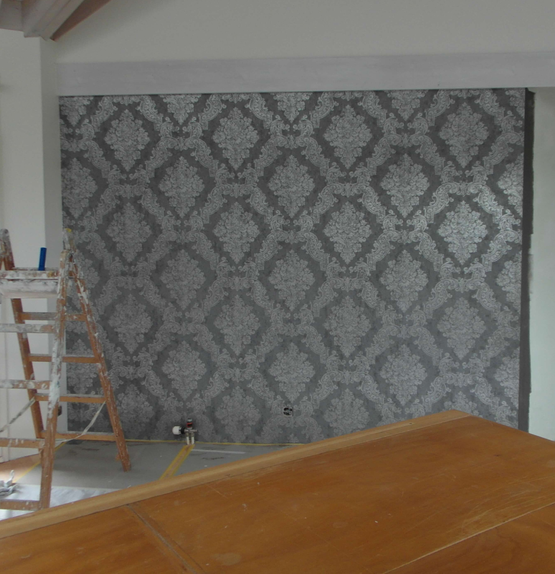 Eine grafische Fototapete mit Pflanzen, Vogel und Blumen. Davor ein grünes Sofa.