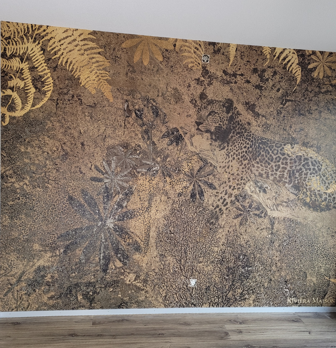 Eine grafische Fototapete mit Pflanzen, Vogel und Blumen. Davor ein grünes Sofa.