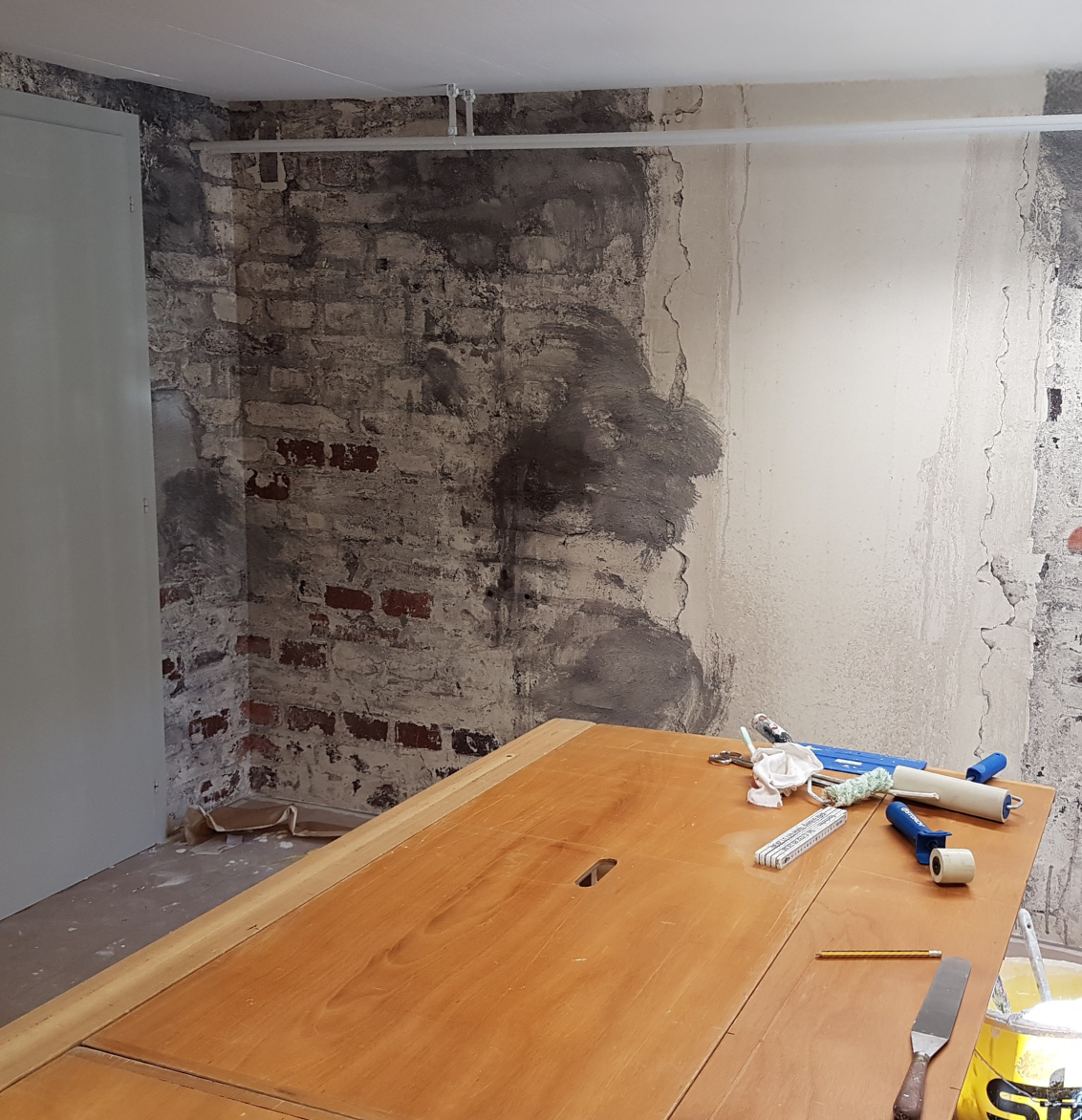 Eine grafische Fototapete mit Pflanzen, Vogel und Blumen. Davor ein grünes Sofa.