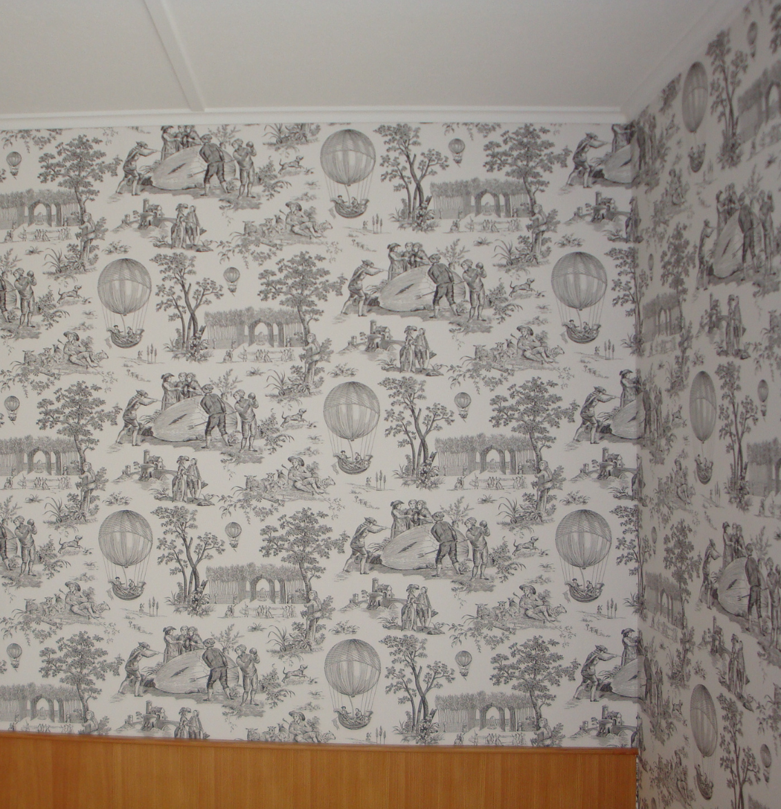 Eine grafische Fototapete mit Pflanzen, Vogel und Blumen. Davor ein grünes Sofa.