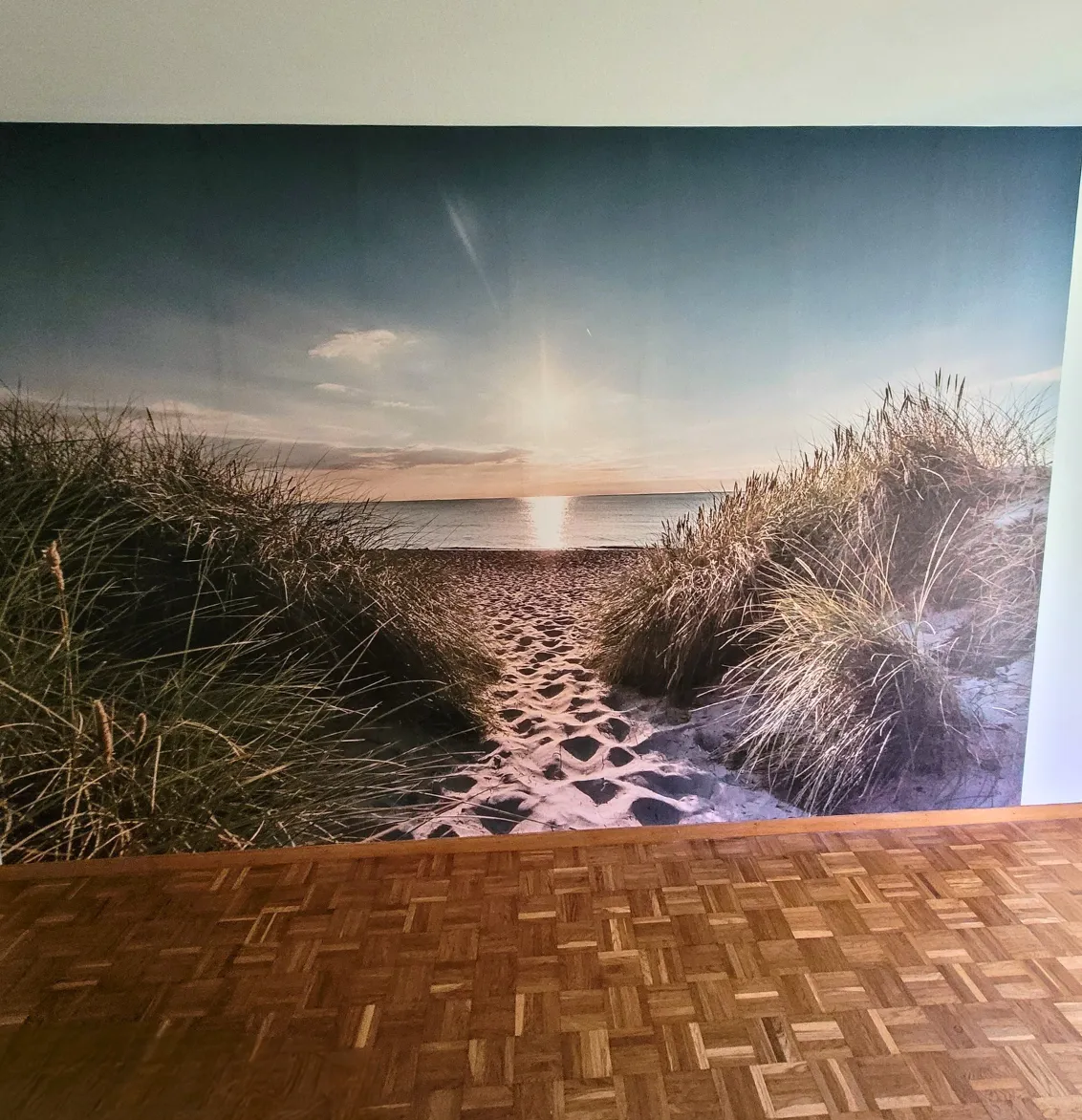 Eine grafische Fototapete mit Pflanzen, Vogel und Blumen. Davor ein grünes Sofa.