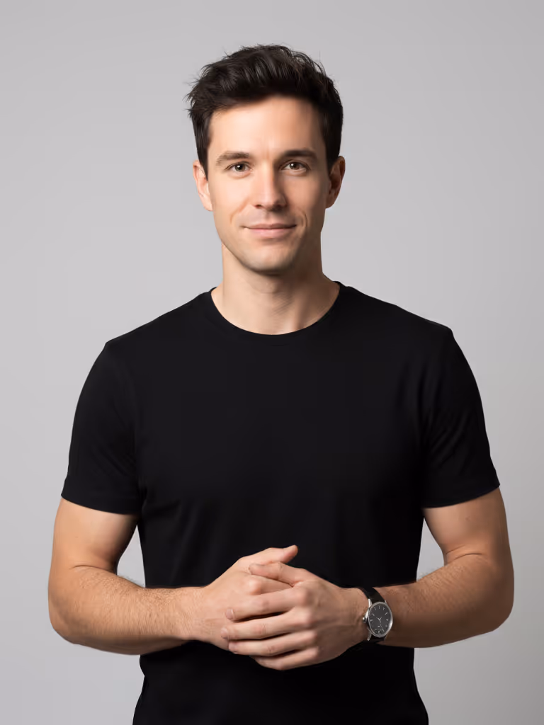 Smiling man with dark hair in a black t-shirt clasping his hands against a gray background.