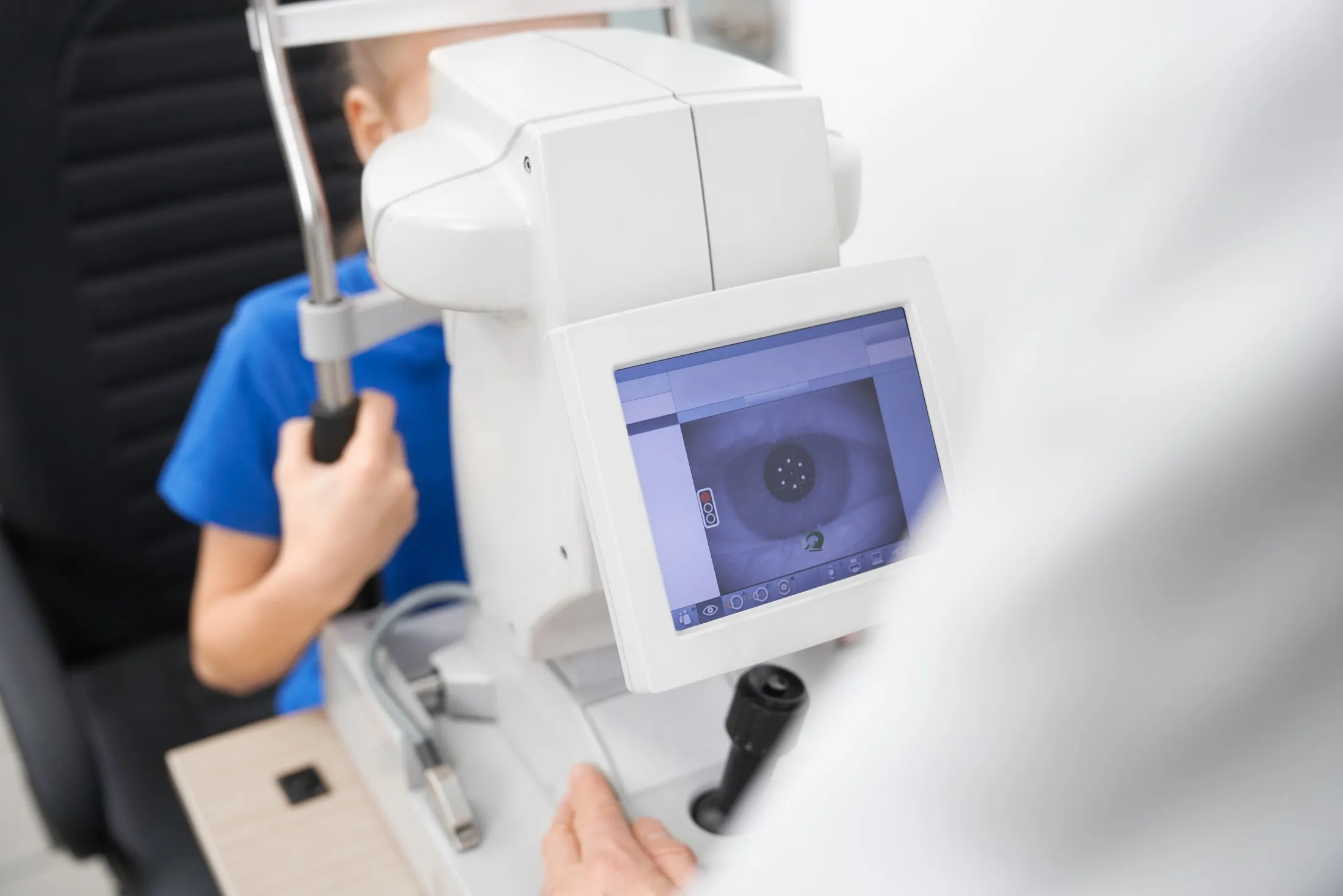 Machine displaying an eye image during an eyesight test with a person holding the device handle.