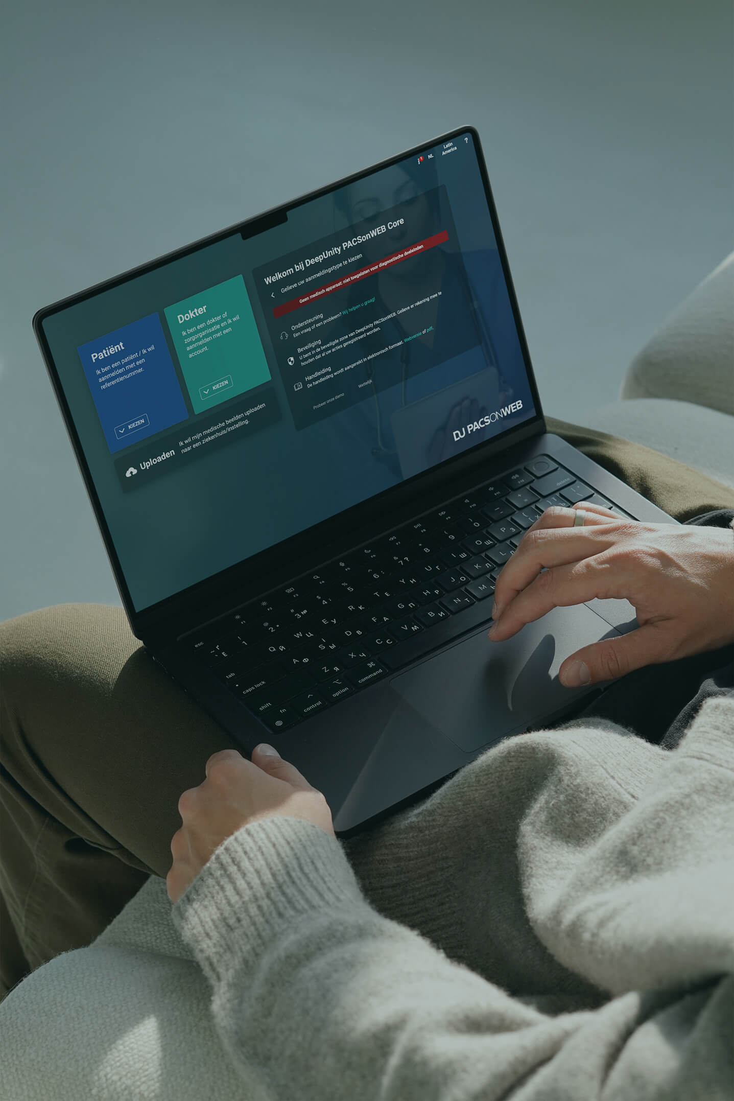 Iemand gebruikt een laptop met het DeepUnity PACsonWEB Core platform voor patiënten- en doktersaanmelding.