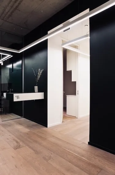 Moderner Eingangsbereich mit schwarzer und weißer Wandgestaltung, Holzfußboden und minimalistischer Dekoration.